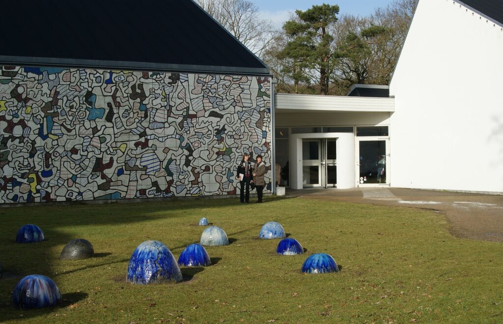 Facciata del Museum Jorn di Silkeborg con murale ceramico e sculture in gres sul prato
